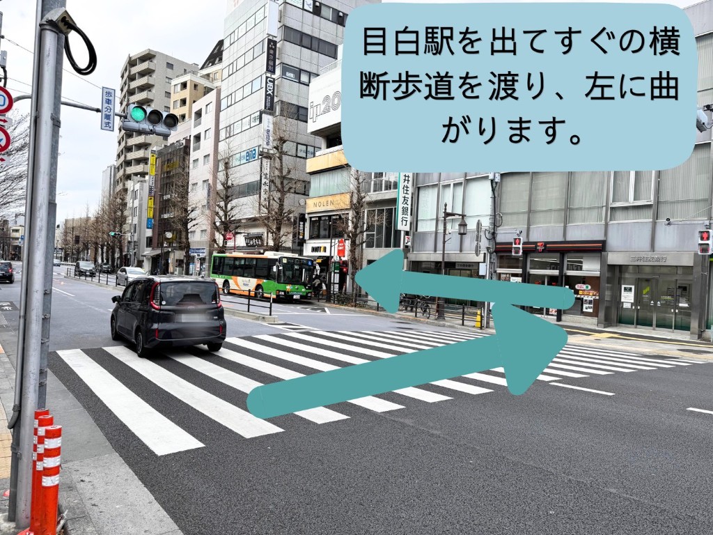 目白駅を出てすぐの横断歩道を渡り、左に曲がる案内。横断歩道と周辺の店舗が写っています。
