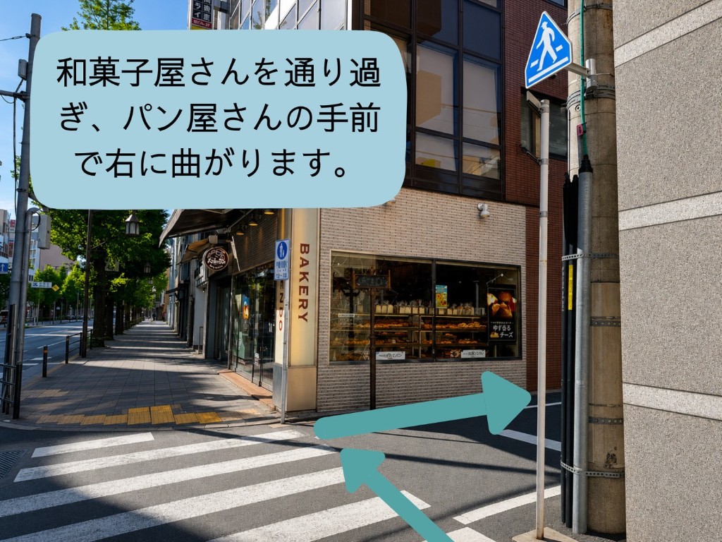 和菓子屋を通り過ぎ、パン屋の手前で右に曲がる案内。角のパン屋が目印です。