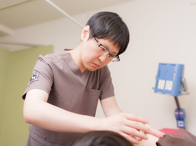 スクラブ姿の院長が患者さまに施術を行っている様子。