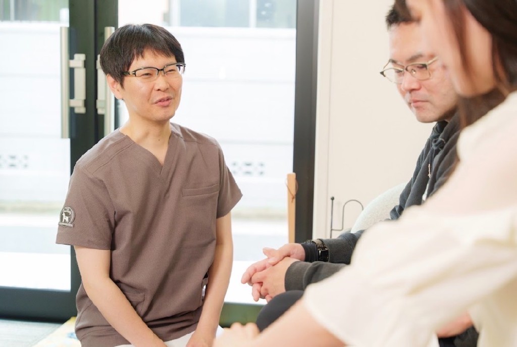 明るい院内で、施術者がご夫婦と対話している様子。