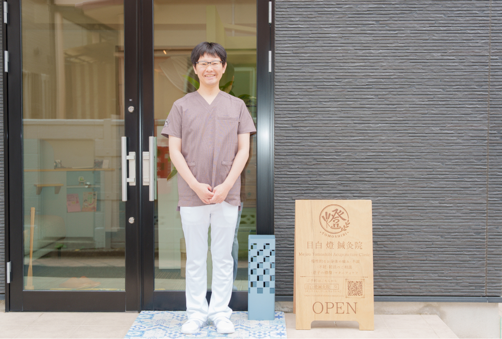 院長のポートレート。明るい院内で、スクラブ姿で微笑んでいる様子。