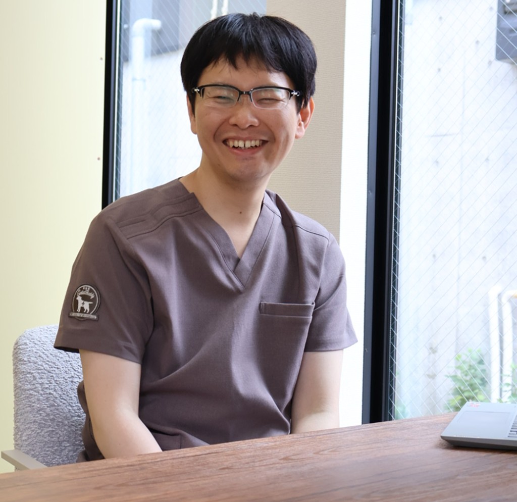 院長のポートレート。明るい院内で、スクラブ姿で微笑んでいる様子。